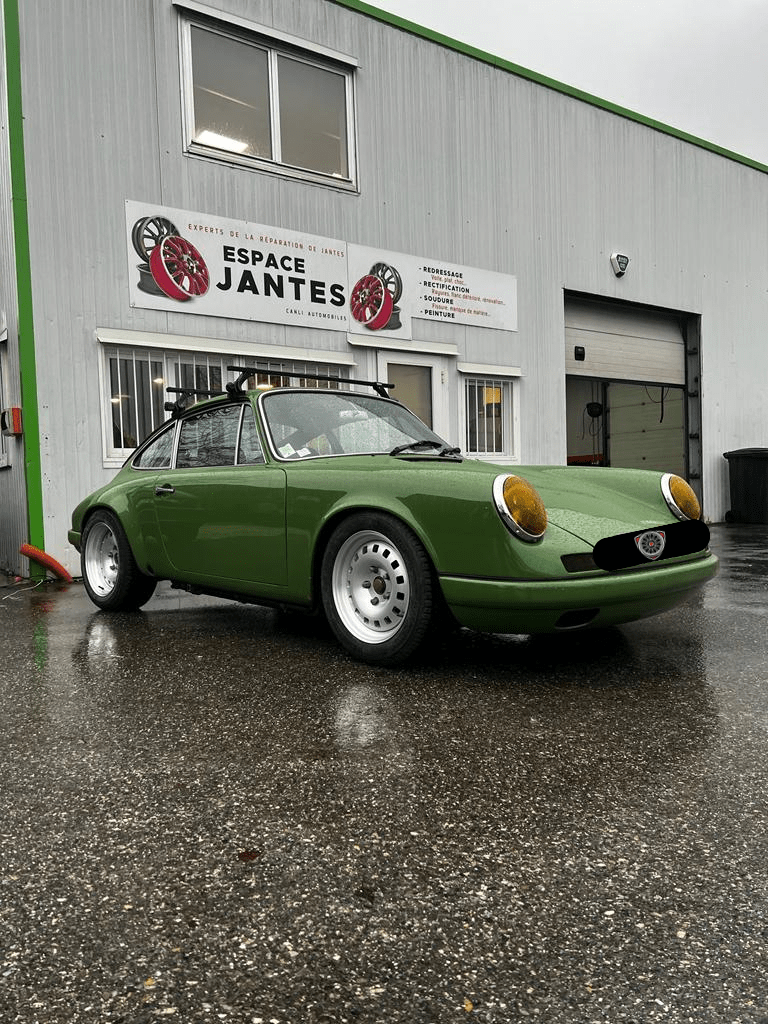Porsche vintage de couleur verte stationnée devant l'atelier Espace Jantes, mettant en avant les services de réparation et de personnalisation de jantes.